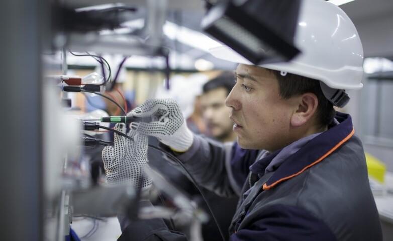 A technician wearing safety gear working on electrical components in an industrial setting as part of a technical cooperation initiative.