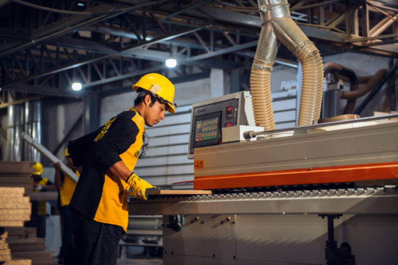 Un empleado de una empresa utiliza un torno para madera.
