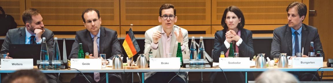 Brasilianische and deutsche Vertreter*innen sitzen an Tischen und tauschen sich im Digitaldialog aus.