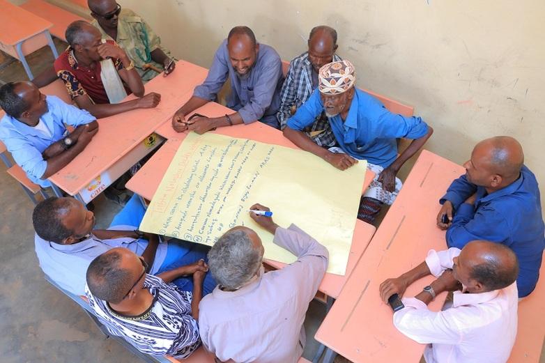Men sit together and discuss FGM.