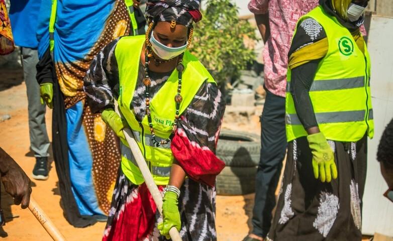 A refugee woman volunteering in the cleanliness campaign and waste collection.