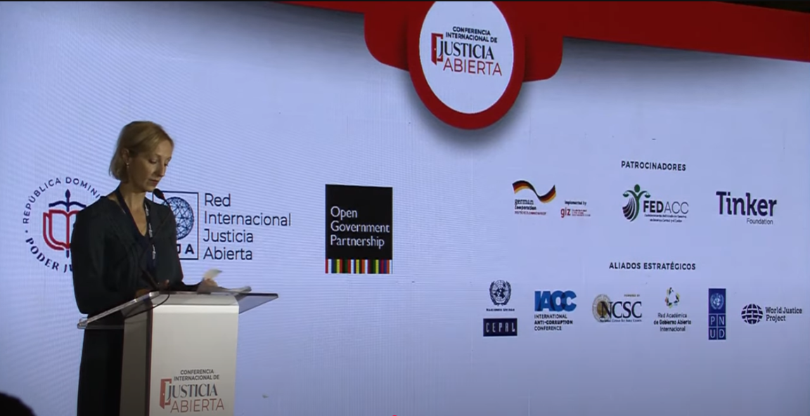 A woman speaking on stage during an international conference on open justice.