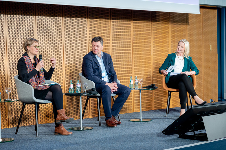 Die D-EITI Sonderbeauftragte und Parlamentarische Staatssekretärin Dr. Franziska Brantner diskutiert mit zwei Personen auf dem BDI-Rohstoffkongress. 