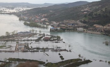 Luftaufnahme eines überschwemmten Gebiets in Shkodra, Albanien, mit überfluteten Feldern und Gebäuden in der Nähe eines Flusses.