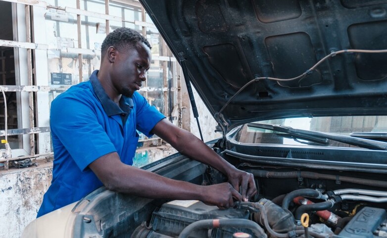 Ein Auszubildender repariert einen Automotor.