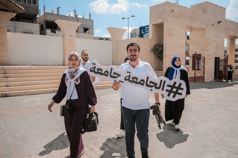 Teilnehmer*innen des Projekts „Inclusive University Campaign” halten ein Schild mit der Aufschrift „Eine Universität ist für alle da“ in der Hand.