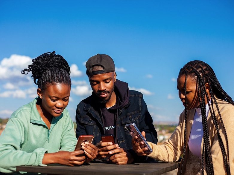 Drei junge Menschen schauen auf ihre Smartphones.