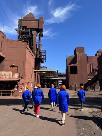 Fünf Personen einer Delegation des Bundesministeriums für Wirtschaft und Klimaschutz besuchen in Schutzkleidung eine Anlage zur CO2-neutralen Reduktion von Eisenerz in Saldanha Bay, Südafrika.