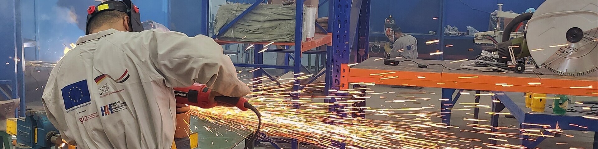 Ein Arbeiter in Schutzkleidung bei Metallarbeiten in einer Industrieanlage.