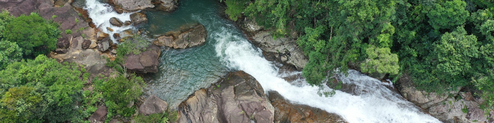 Ein Bergfluss fließt zwischen Bäumen in Vietnam.