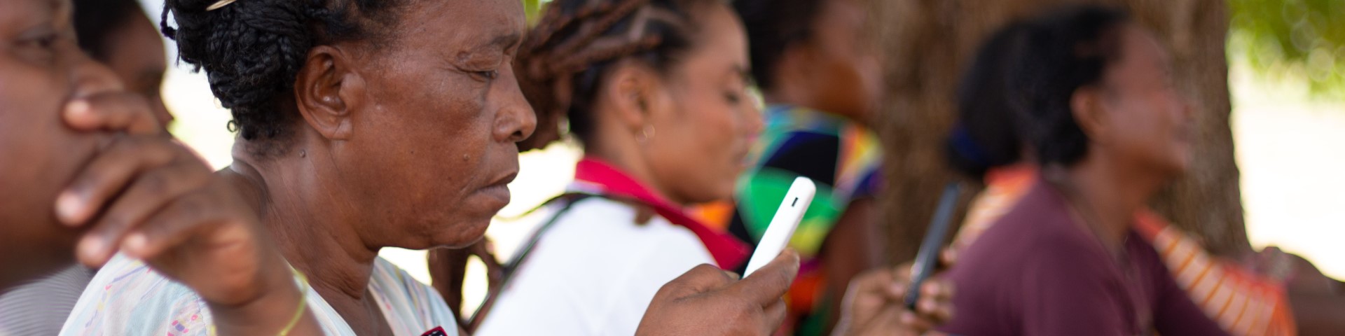 Frauen sitzen zusammen und schauen auf Smartphones.