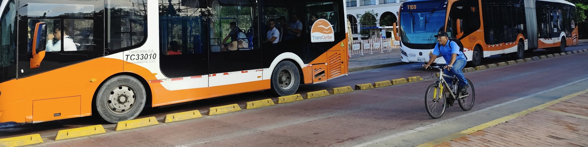 Nachhaltiger Stadtverkehr in Cartagena, Kolumbien: Nahverkehrsbusse fahren auf einer getrennten Spur neben einem Fahrradfahrer.