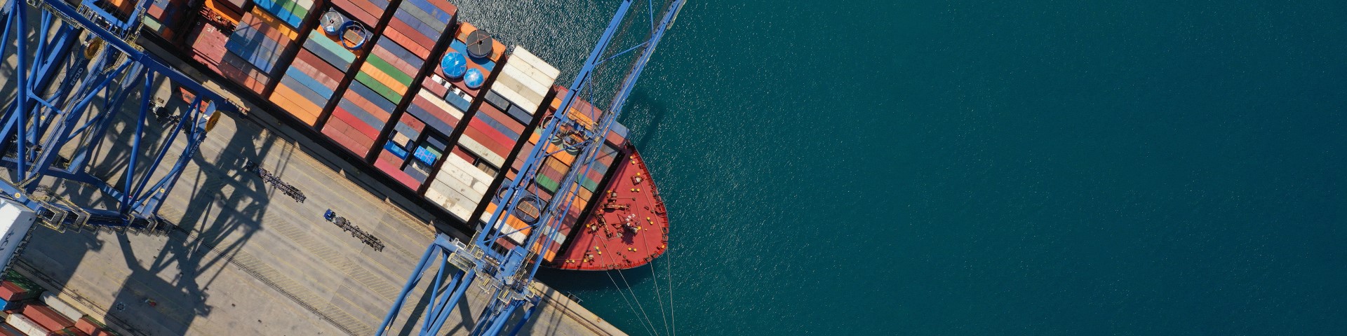 Vogelperspektive auf ein Containerschiff, das in einem Containerhafen liegt.