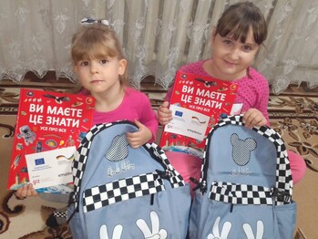 Two girls at primary school showing the classroom equipment they have received