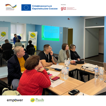 People sitting together around tables during a training session. Project partner logos are shown at the edge of the photo.