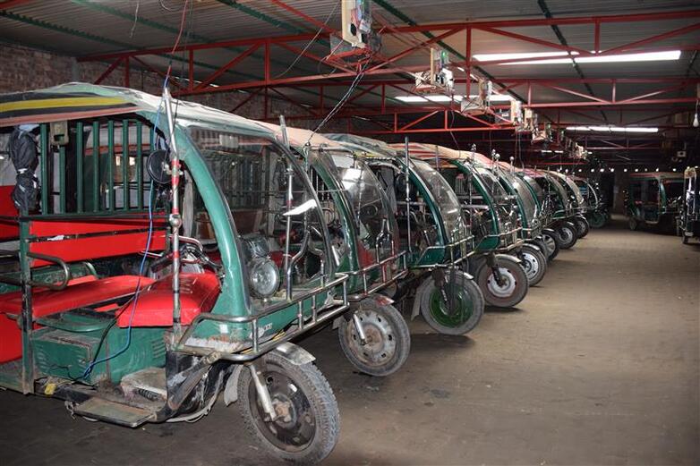 Electric rickshaws are parked in a garage.