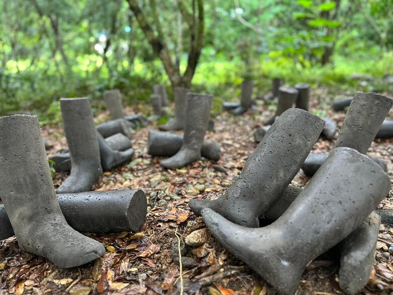 Un monumento conmemorativo con botas de guerrilleros y guerrilleras moldeadas en cemento.