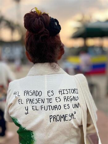 Una mujer viste una camiseta con un texto de recuerdo a las víctimas escrito en la espalda.