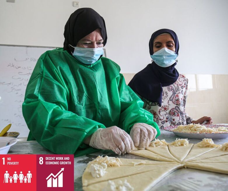 Two people in protective clothes working dough.