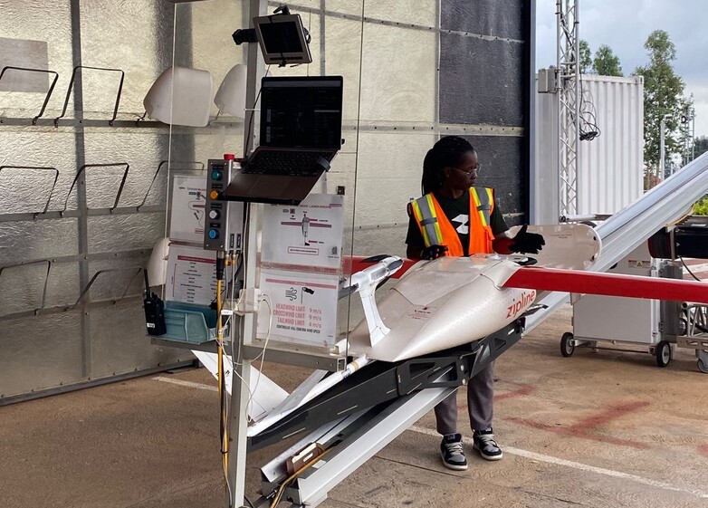 A person stands next to a drone in a workshop.