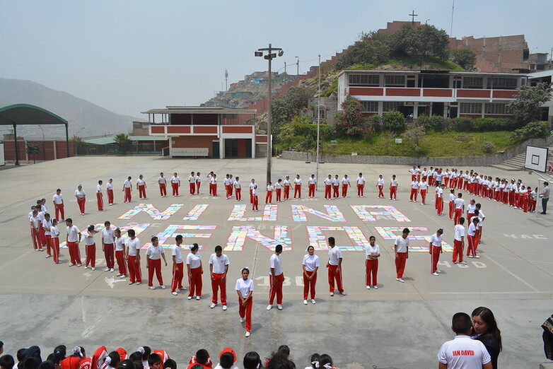 Children in a school playground form a heart around the words ‘Ni una menos’.