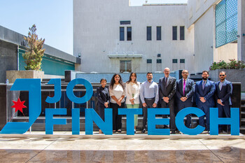 I-FIN team standing in front of a 'Jo Fintech' sign at the Central Bank of Jordan building.