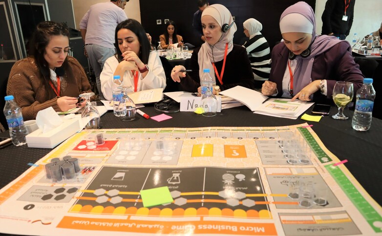 Five women participating in a board game during DSIK capacity building training.