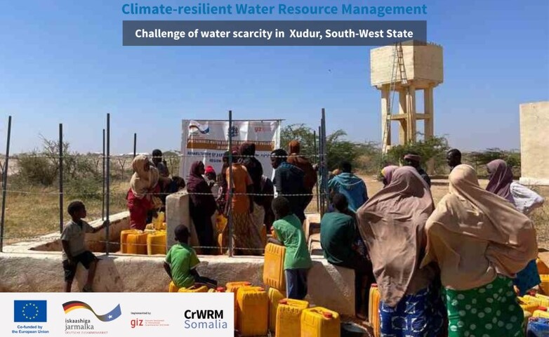 Community members in Xudur, South-West State, queue with yellow jerrycans to access water near a water tower.