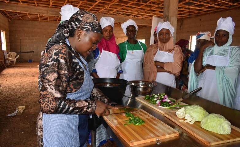 A group of women participate in a cheese training session, with one woman chopping vegetables on a cutting board.