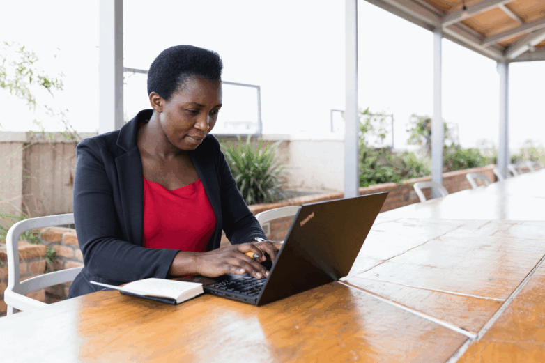 Une femme est assise devant un ordinateur portable et tape au clavier.