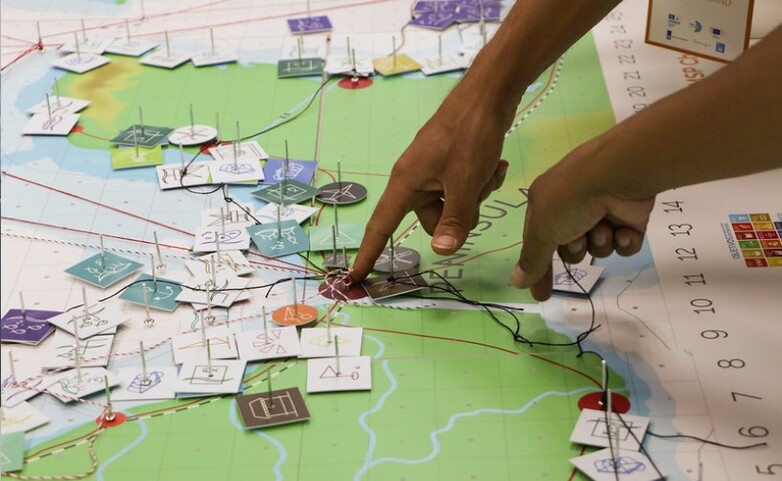 Close-up of hands engaging in Marine Spatial Planning using a detailed map with various markers representing maritime activities and resources.