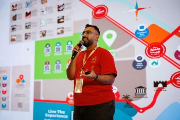 A Jordanian entrepreneur pitching his company while standing in front of a large screen displaying a presentation.