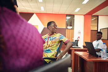 IT specialists sit in front of laptops in a seminar room and talk.