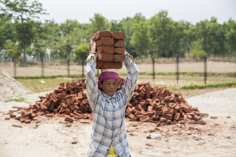 A woman carrying bricks on her head.