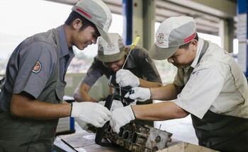 An in-company trainer supervises students while they practice in the Automotive Mechanic course.