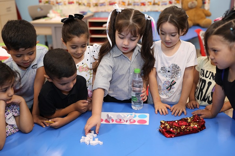 Children play an educational game at a table in a classroom.