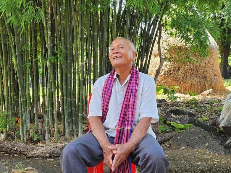 A survivor of the Khmer Rouge regime sits at a mass grave and shares oral histories.