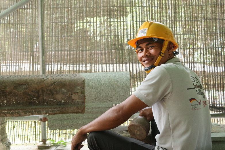 A stone conservation apprentice works on a pillar in the temples of Angkor.