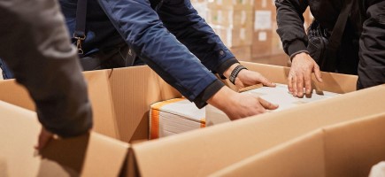 Hands reach into a large cardboard box