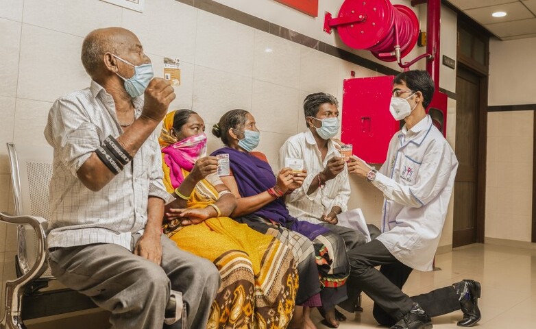 A male nurse distributes Ayushman Cards, providing health insurance coverage to patients in India.