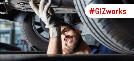 A vehicle mechanic repairing a car exhaust,