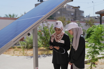 Two young trainees working on a solar module.