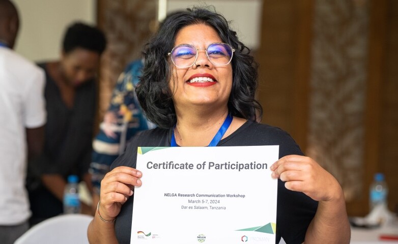 A participant holding a Certificate of Participation from the NELGA Research Communication Workshop held in March 2024 in Dar es Salaam, Tanzania.