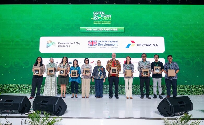 A group of individuals standing on a stage holding boxes during the Green Economy Expo 2024.