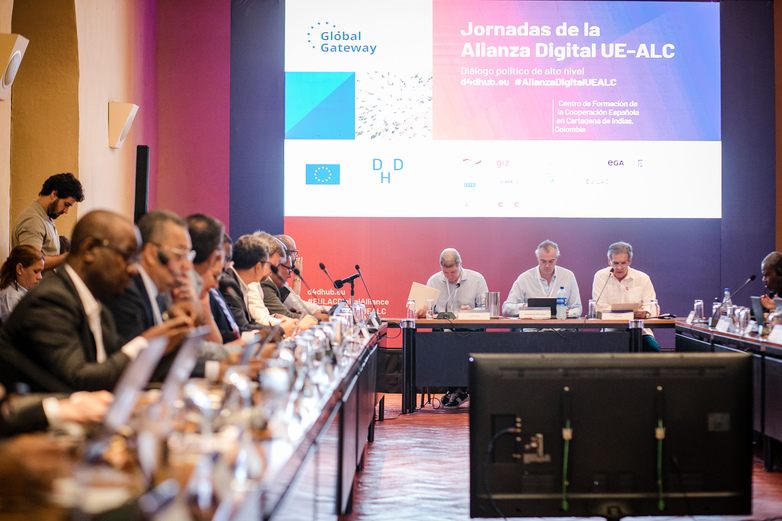 Representantes sentados y sentadas juntos en las “Jornadas de la Alianza Digital UE-ALC”.  En una de las paredes se puede ver una presentación.