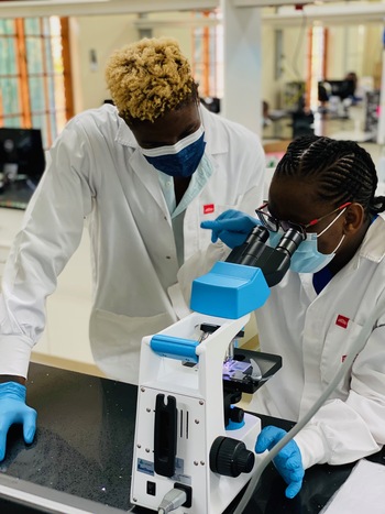 Two lab workers operating a microscope.