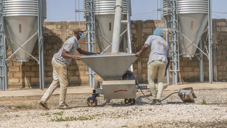 Two men produce animal feed.