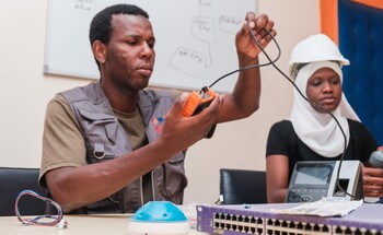 Two students work with electrical equipment in a technical setting.