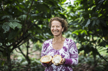 A woman holds a ripe, opened cocoa fruit in her hands.