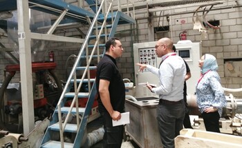 Four people discuss and inspect an industrial facility.